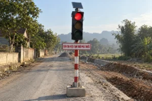 Đèn tín hiệu tạm thời cắm trên cột sơn đỏ trắng, bên dưới là biển trắng viền đỏ chữ Đèn tín hiệu tạm thời phía trước, đường đang sửa