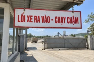 Biển báo đi chậm nền trắng viền đỏ chữ đỏ Lối xe ra vào - chạy chậm, treo xích dưới mái chòi bảo vệ ở cổng công trường