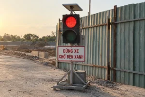 Bảng trắng viền đỏ chữ Dừng xe chờ đèn xanh gắn dưới đèn tín hiệu tạm thời cạnh hàng rào tôn công trường