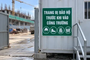 Biển trang bị bảo hộ nền xanh lục chữ trắng, bốn ký hiệu, gắn trên container cạnh cổng công trường