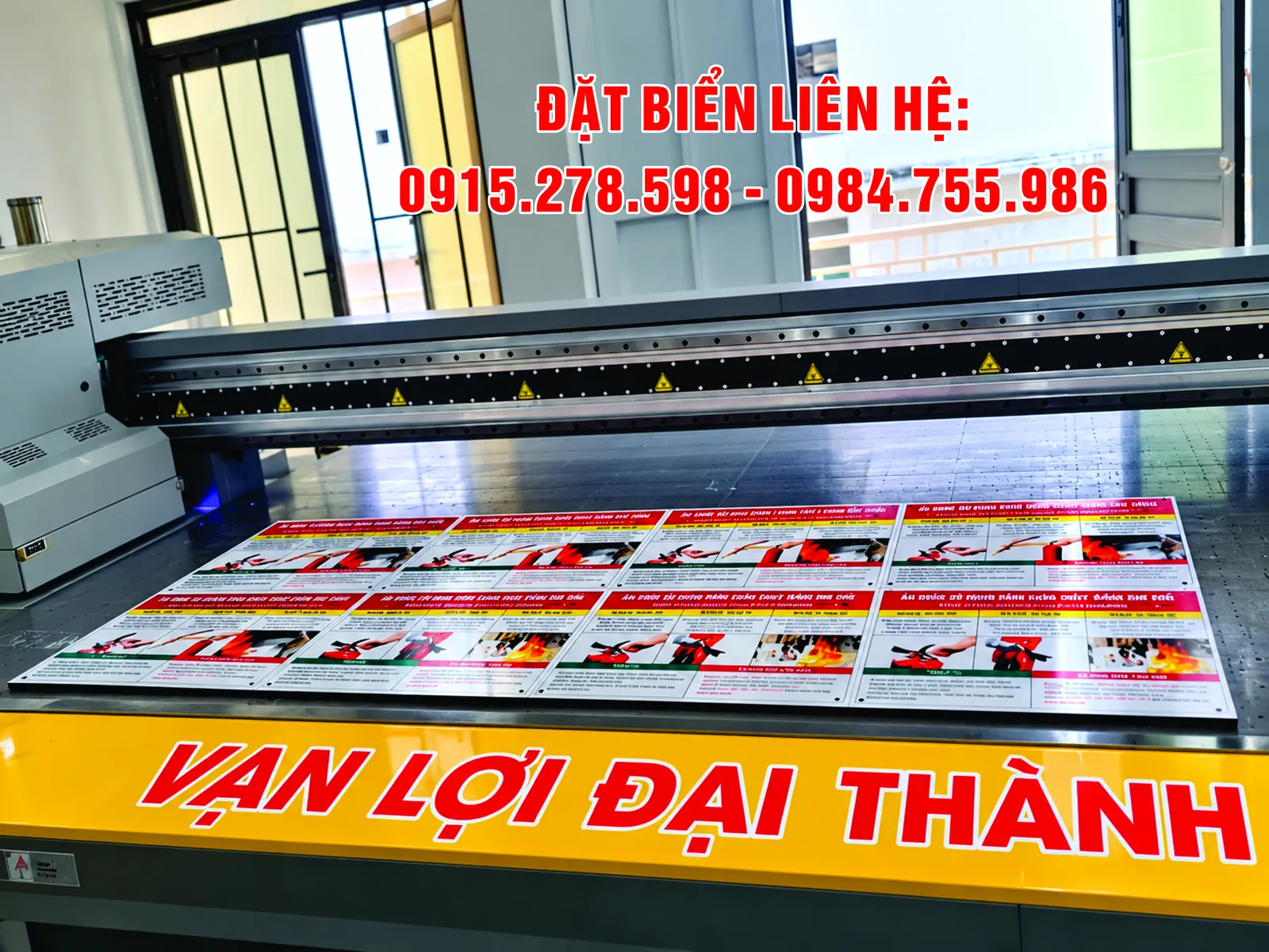 In UV trên alu xước: bàn in của máy in UV phẳng với nhiều bản in màu đỏ trắng xếp thành tấm