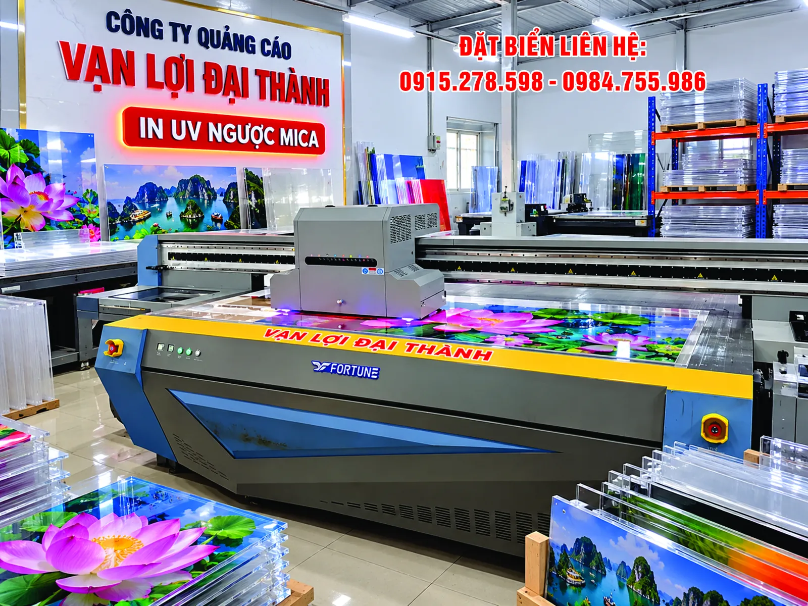 In UV ngược mica trong: tấm mica in hoa sen và tranh phong cảnh đặt cạnh máy in UV phẳng