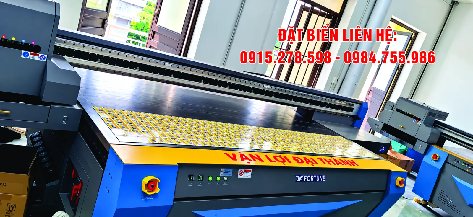 In UV trên tôn: máy in UV phẳng khổ lớn với bàn in đang in lô sản phẩm nhỏ
