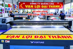Xưởng in UV phẳng với máy in khổ lớn đang in lô sản phẩm trên bàn in